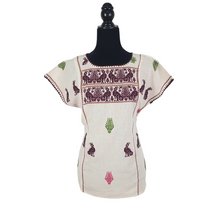 Cargar imagen en el visor de la galería, Blusa grande de corte recto con bordados de hilván tradicionales de Puebla, en color blanco con detalles en pecho, mangas y parte inferior. Hecha por Hilaria Gómez.