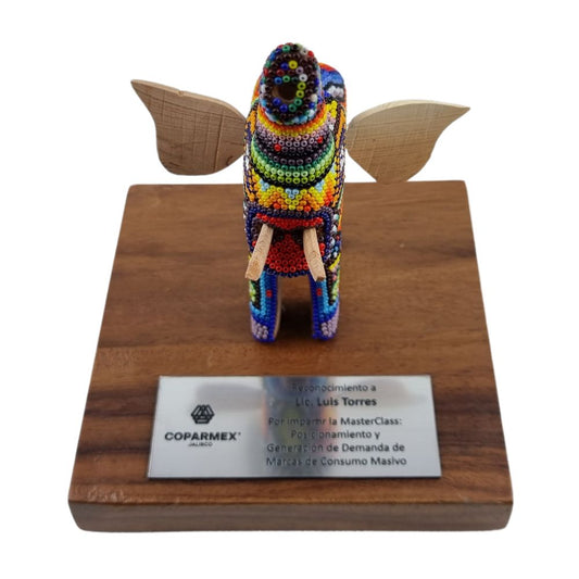 Reconocimiento con artesanía mexicana. Elefante wixárika en trofeo con base de madera y placa metálica personalizada