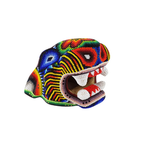 Cabeza de jaguar hecha de madera tallada a mano y decorada con motivos wixárika