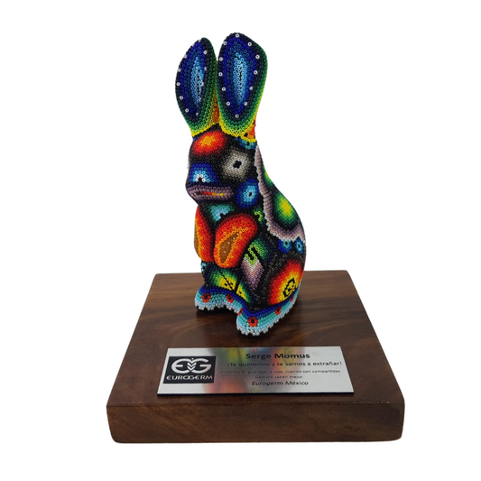 Reconocimiento con artesanía mexicana. Conejo decorado con arte wixárika, en trofeo con base de madera y placa metálica personalizada