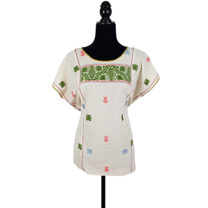 Blusa grande de corte recto con bordados de hilván tradicionales de Puebla, en color blanco con detalles en pecho, mangas y parte inferior. Hecha por Hilaria Gómez.