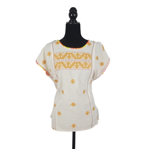 Blusa grande de corte recto con bordados de hilván tradicionales de Puebla, en color blanco con detalles en pecho, mangas y parte inferior. Hecha por Hilaria Gómez.