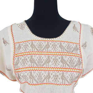 Blusa grande de corte recto con bordados de hilván tradicionales de Puebla, en color blanco con detalles en pecho, mangas y parte inferior. Hecha por Hilaria Gómez.