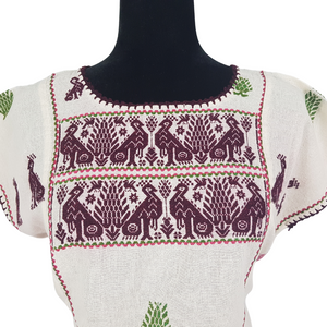 Blusa grande de corte recto con bordados de hilván tradicionales de Puebla, en color blanco con detalles en pecho, mangas y parte inferior. Hecha por Hilaria Gómez.